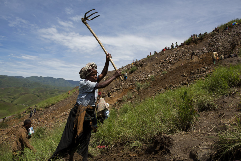  En kvinna rensar undan jorden och förbereder för ännu ett gruvhål.