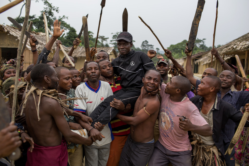 Kazimoto Masudi, i svart, är ledare för gruppen i byn. Han säger att de bara slåss med knivar, påkar och machetes, men många unga soldater med automatgevär sågs i byn.